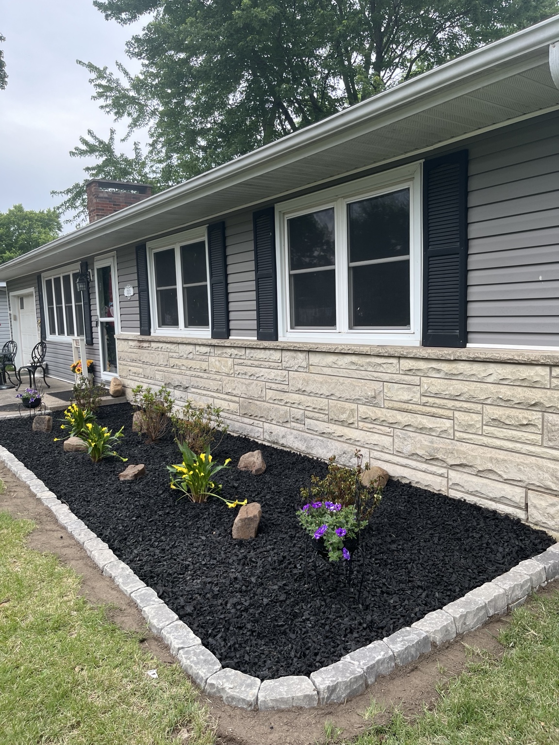 Black mulch landscape bed with stone edging